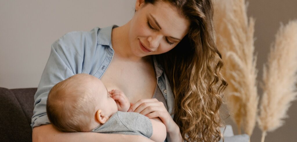 Jeune mère allaitant son enfant, habillé, de quelques mois