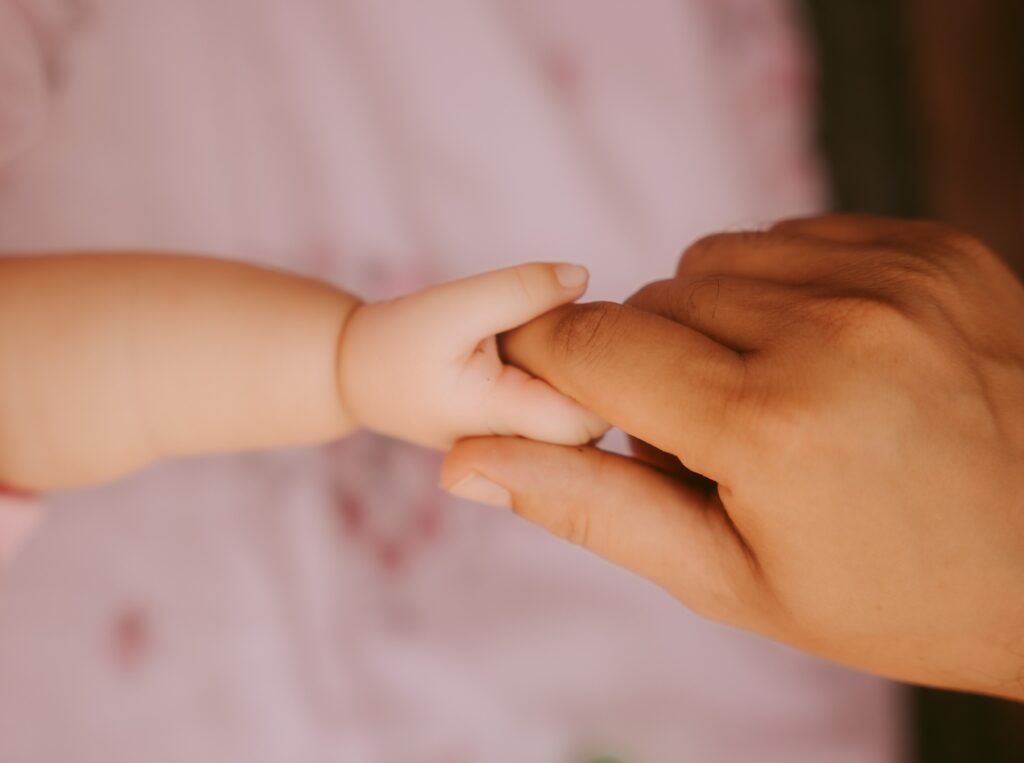 La main de maman tient et accompagne celle de son enfant bébé