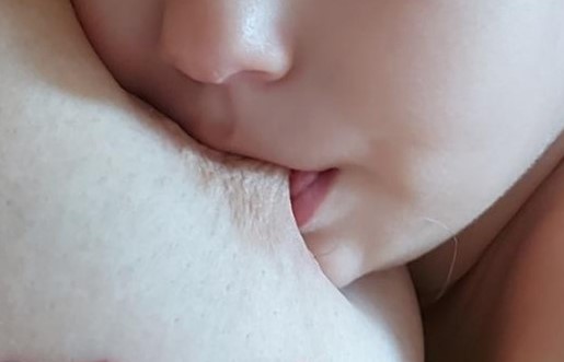 Visage d'un bébé au sein de sa mÚre on voit le mamelon pris par l'enfant pour l'allaitement maternel